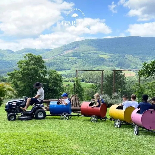 Trenzinho puxado por trator passeando pelo gramado com vista para o vale